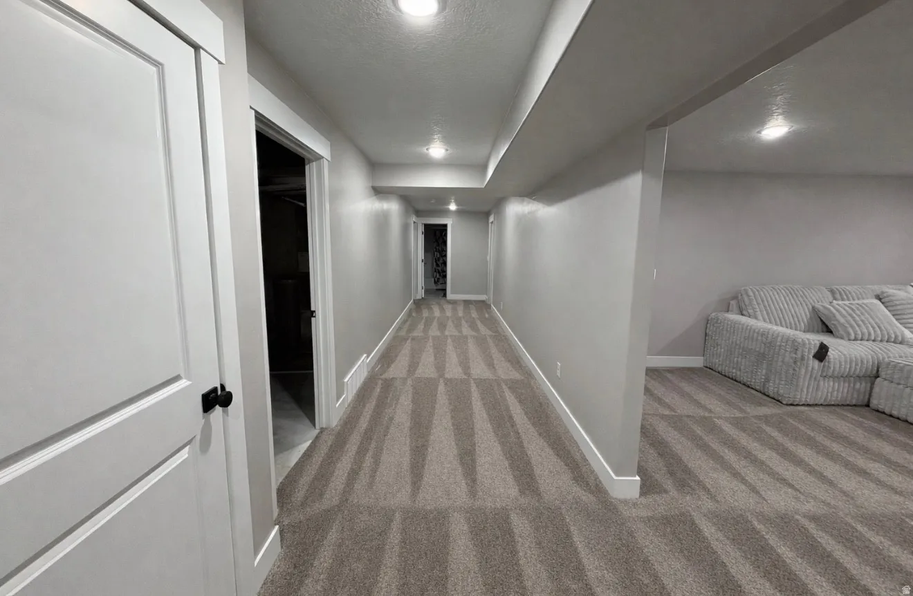 Corridor featuring light carpet, a textured ceiling, and recessed lighting