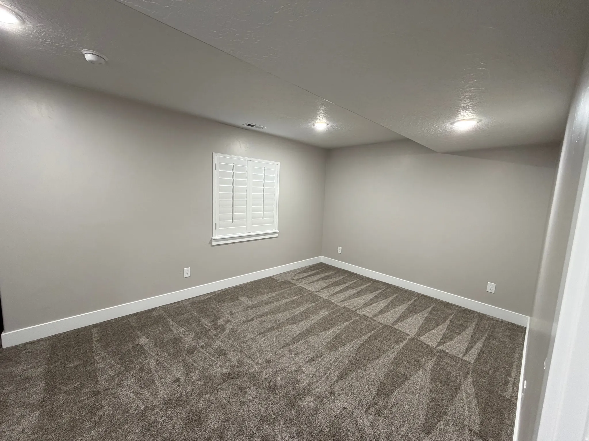 Spare room featuring a textured ceiling and dark carpet