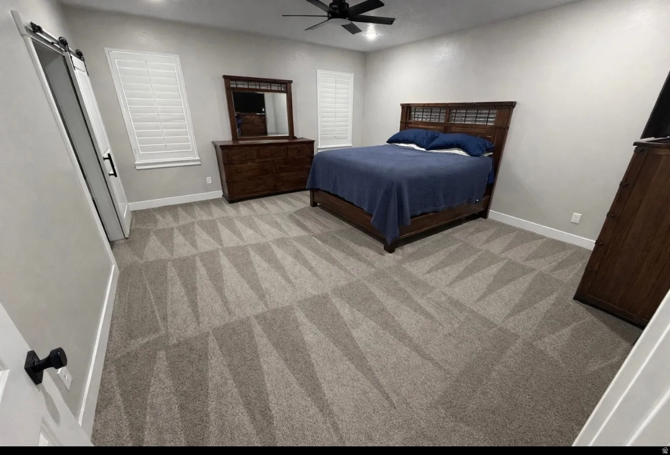 Bedroom with a barn door, a ceiling fan, recessed lighting, and light colored carpet