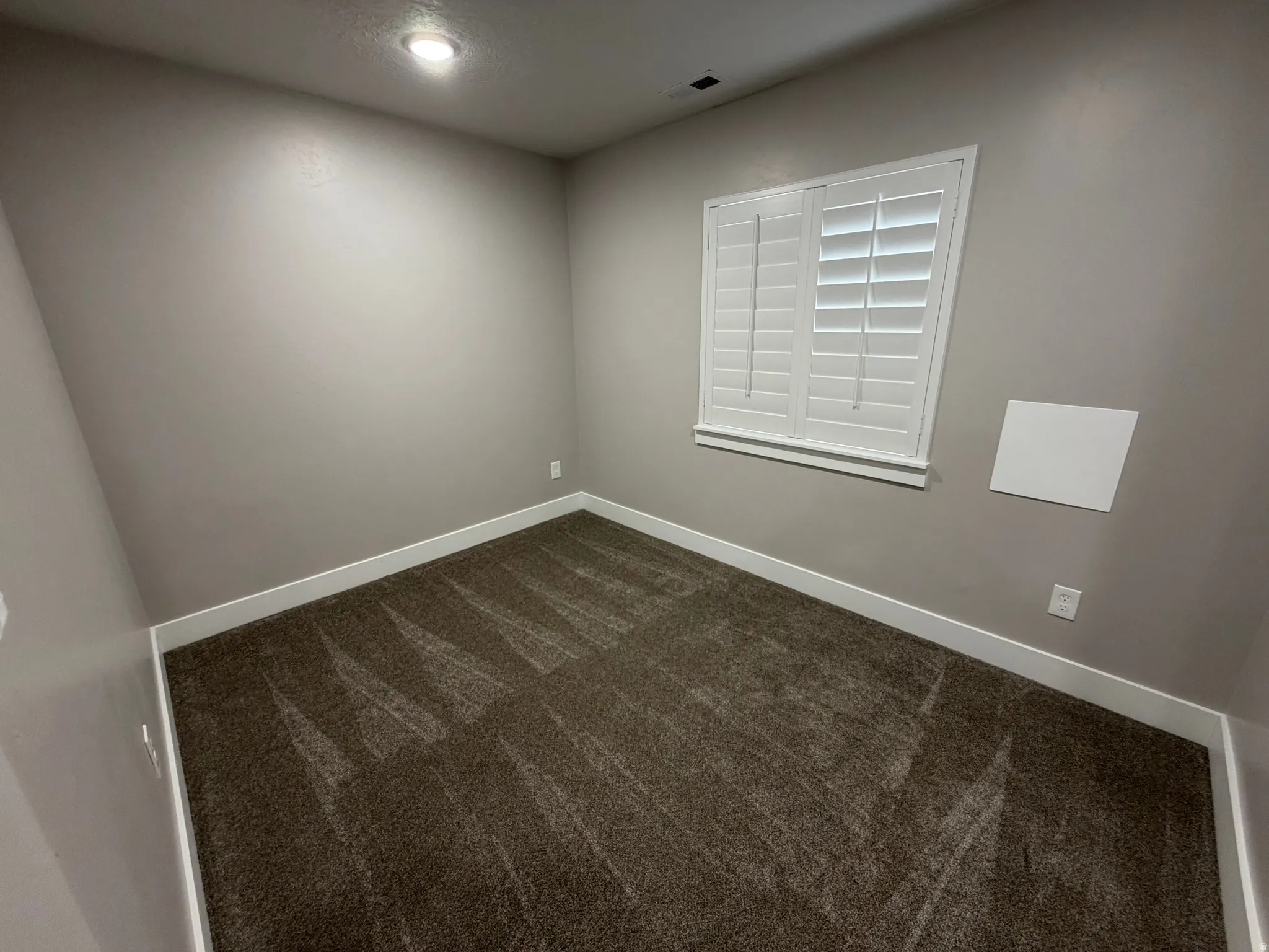 Unfurnished room with dark carpet and baseboards