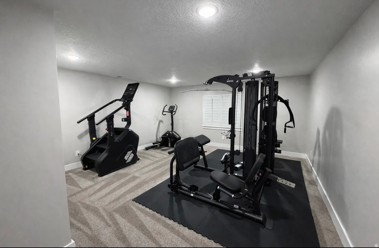 Workout area featuring carpet flooring, a textured ceiling, and recessed lighting