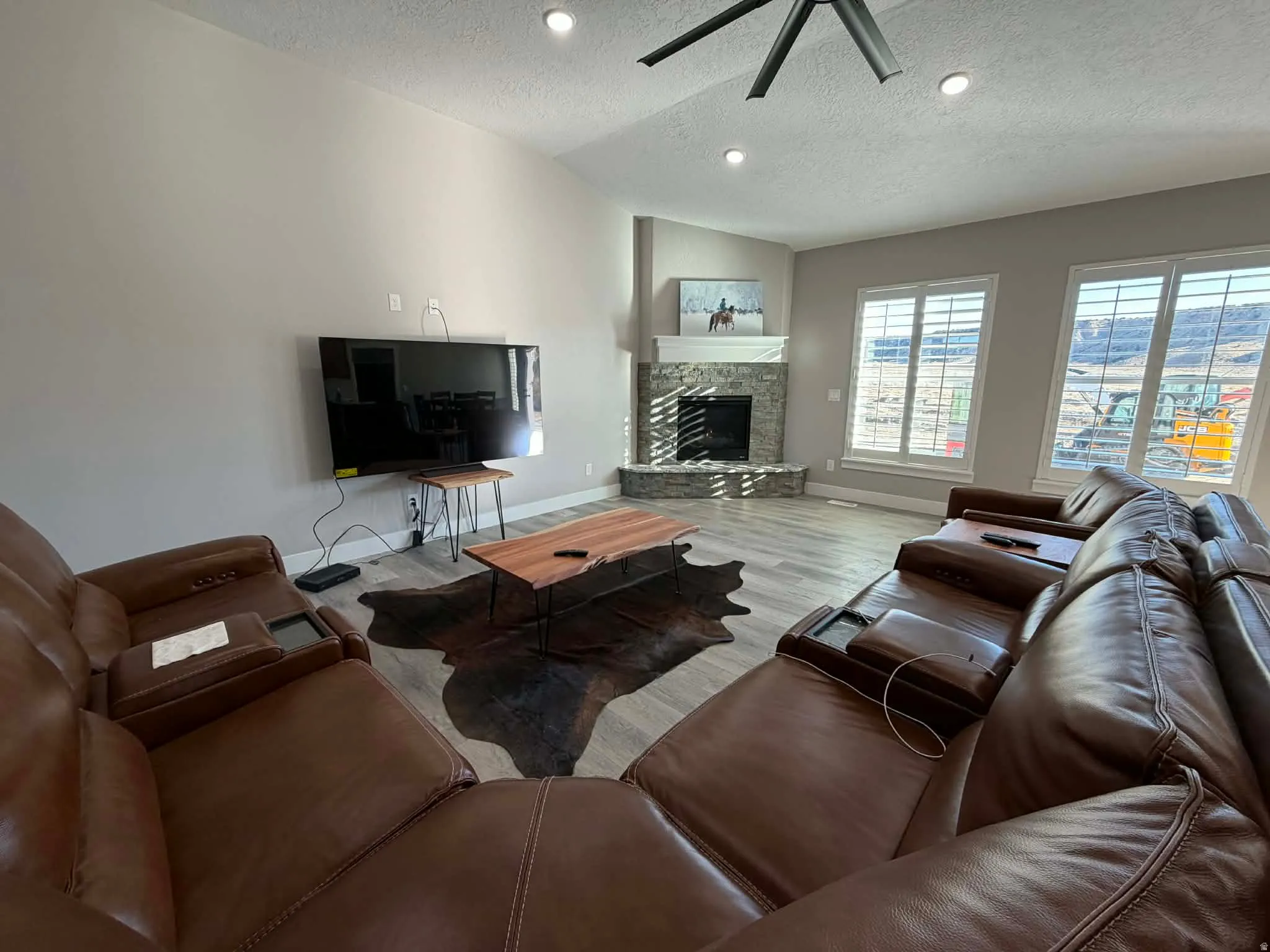 Living area with a textured ceiling, a fireplace, wood finished floors, lofted ceiling, and recessed lighting