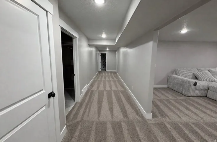Corridor featuring light carpet, a textured ceiling, and recessed lighting