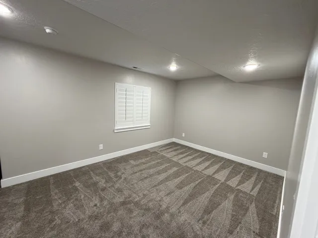 Spare room featuring a textured ceiling and dark carpet