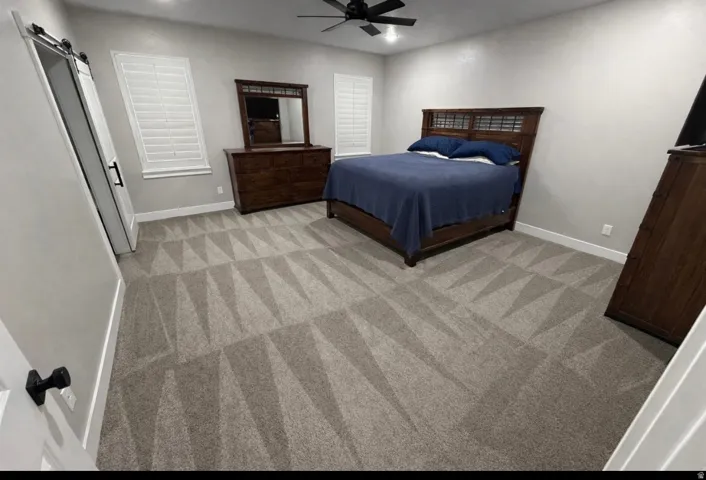 Bedroom with a barn door, a ceiling fan, recessed lighting, and light colored carpet