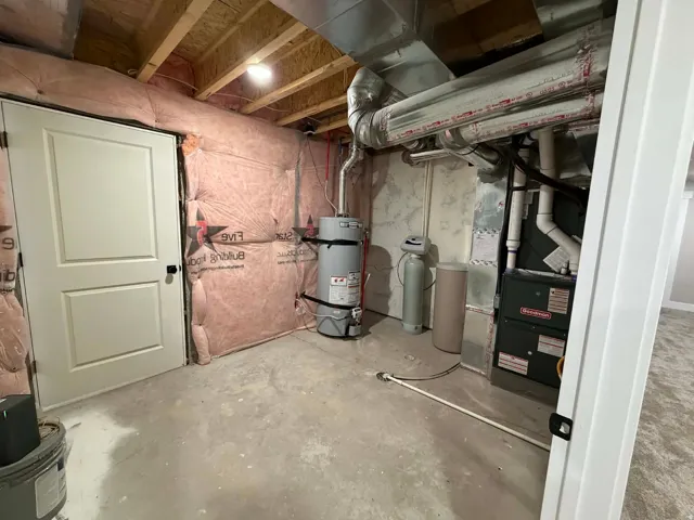 Unfinished basement featuring a water softener, strapped water heater, and heating unit