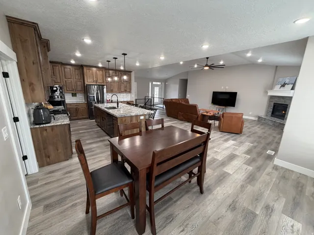 Dining room featuring a textured ceiling, ceiling fan, recessed lighting, light wood-style floors, and a stone fireplace