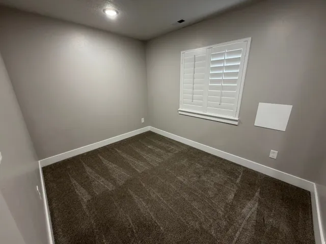 Unfurnished room with dark carpet and baseboards
