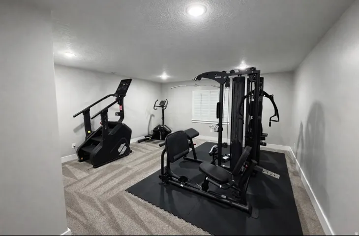 Workout area featuring carpet flooring, a textured ceiling, and recessed lighting