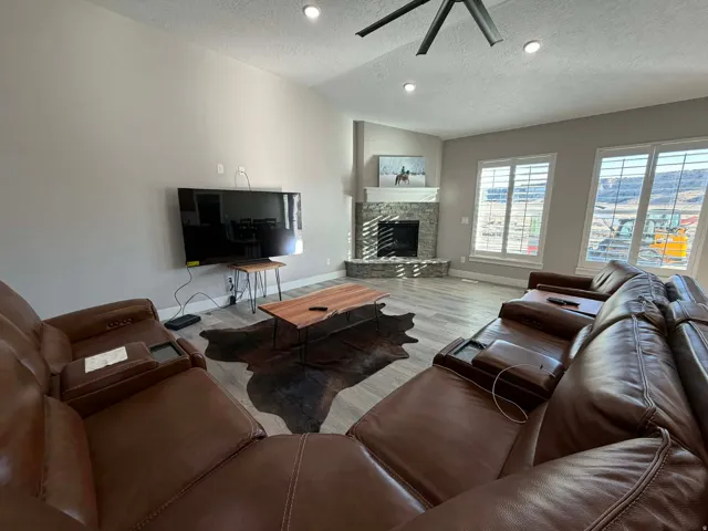 Living area with a textured ceiling, a fireplace, wood finished floors, lofted ceiling, and recessed lighting