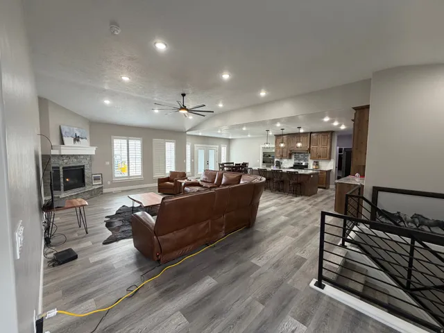 Living area featuring ceiling fan, a fireplace, wood finished floors, vaulted ceiling, and recessed lighting