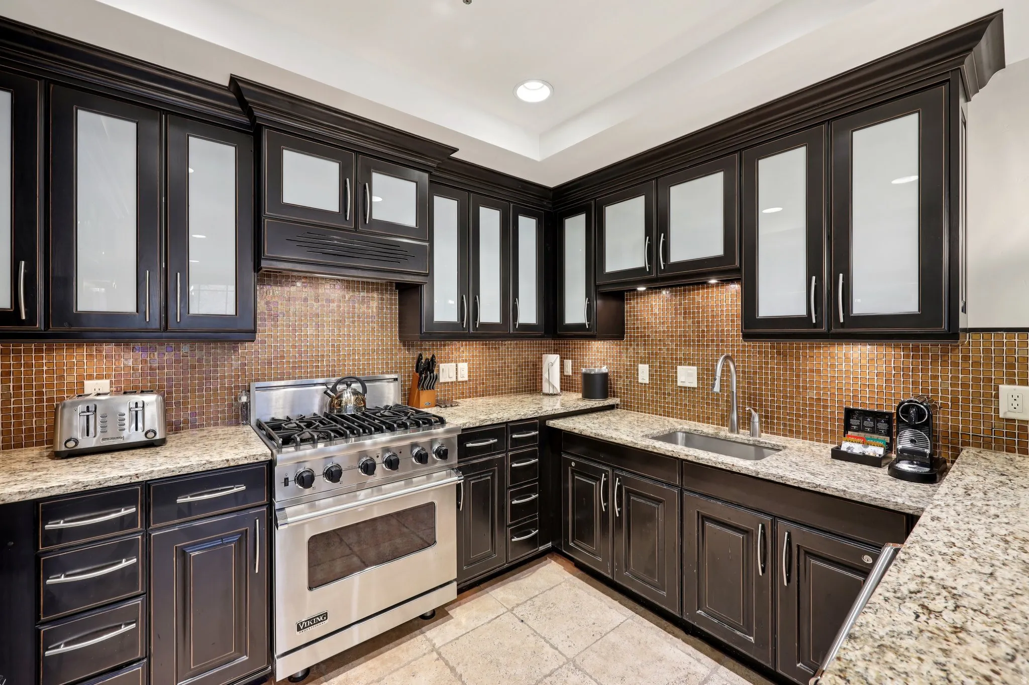 Kitchen featuring glass insert cabinets, luxury range, light stone counters, backsplash, and recessed lighting
