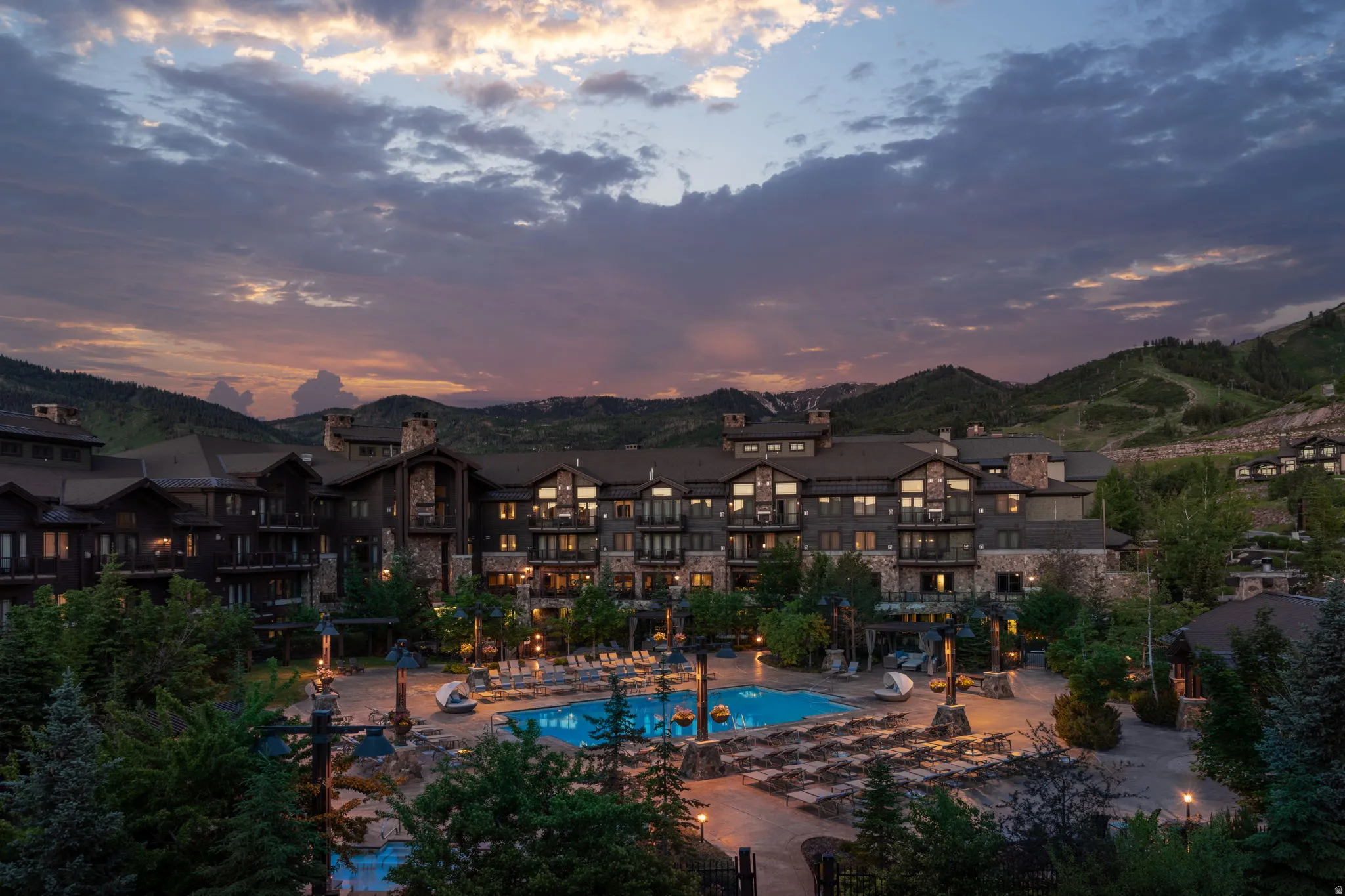 Pool at dusk featuring a community pool, a patio, a mountain view, and a pergola