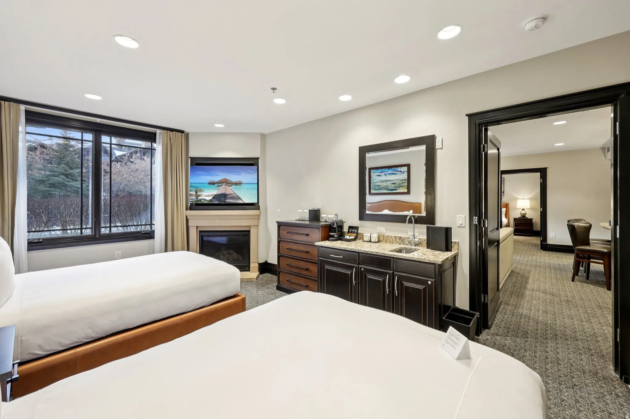 Bedroom with dark colored carpet, a glass covered fireplace, and recessed lighting