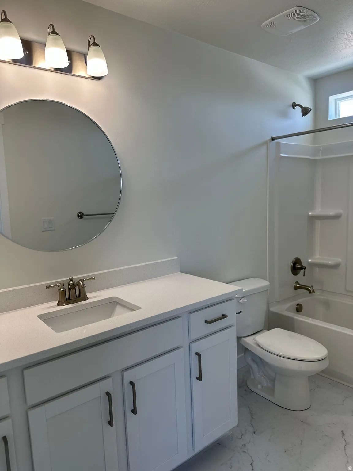 Bathroom with light marble finish flooring, vanity, and shower / tub combination