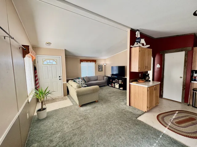 Living area with light carpet and vaulted ceiling