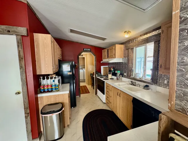 Kitchen featuring light countertops, arched walkways, decorative backsplash, and black appliances