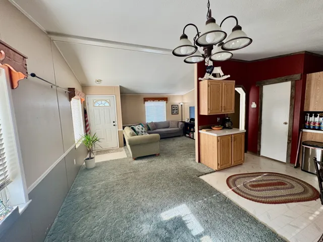 Kitchen featuring light countertops, a chandelier, open floor plan, hanging light fixtures, and light colored carpet