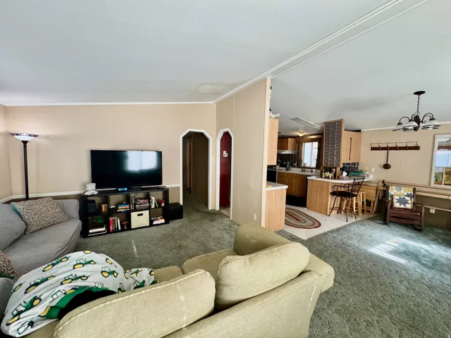 Living area featuring carpet, arched walkways, ornamental molding, healthy amount of natural light, and a chandelier
