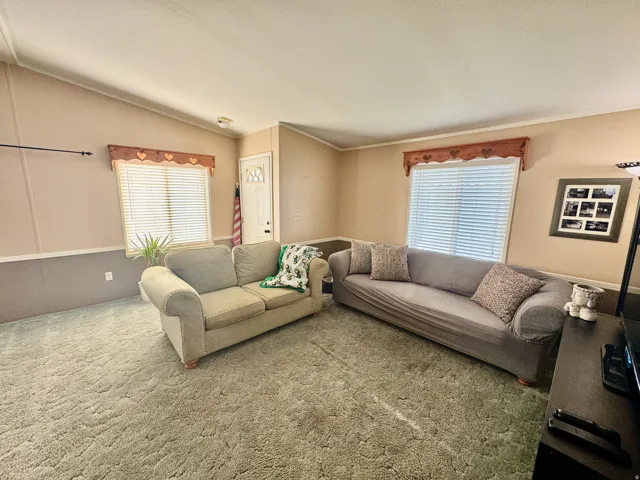 Carpeted living room with plenty of natural light, lofted ceiling, and crown molding