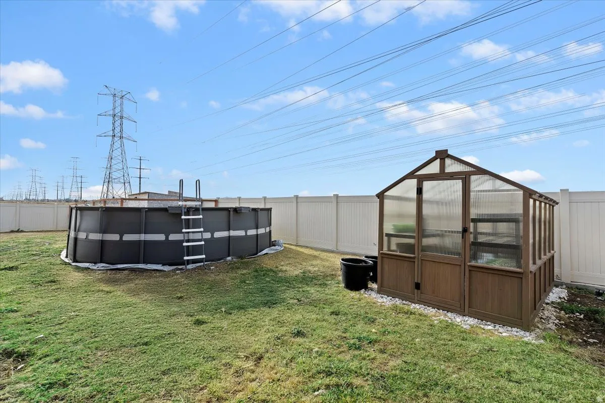 Fenced backyard with a green house, and an new outdoor pool