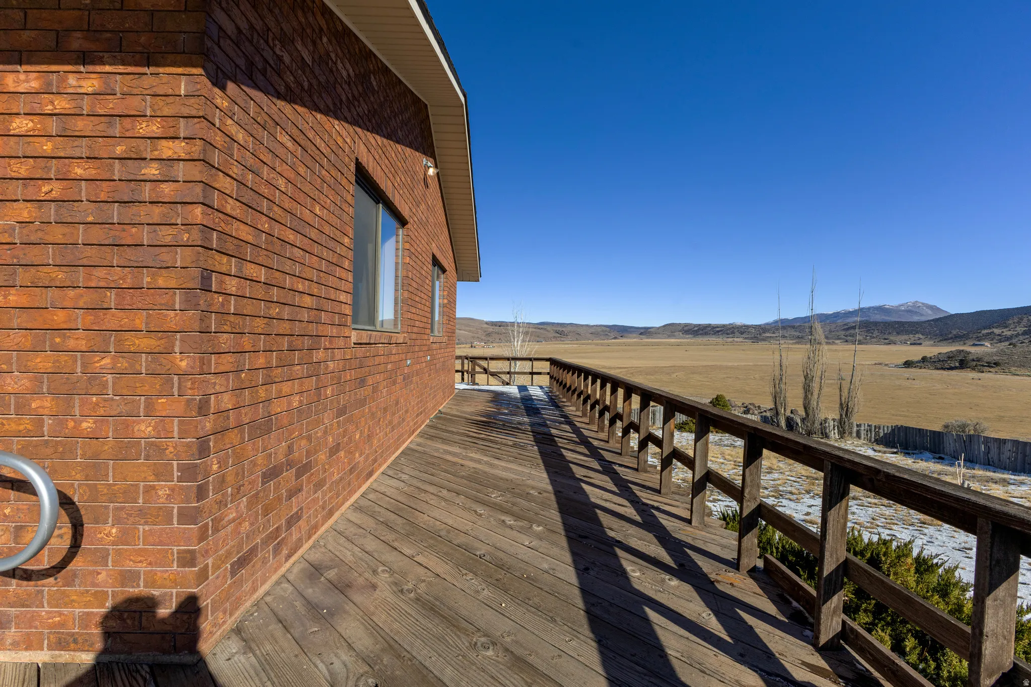 View of home's exterior with a deck with mountain view, brick siding, and a view of rural / pastoral area