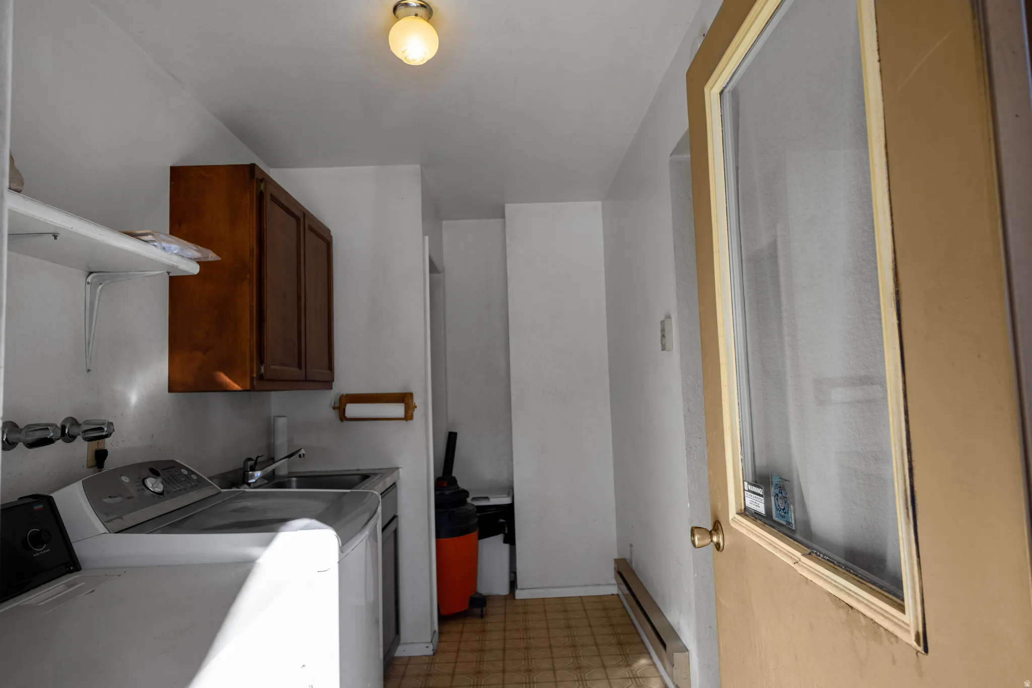 Washroom featuring light floors, baseboard heating, independent washer and dryer, and cabinet space