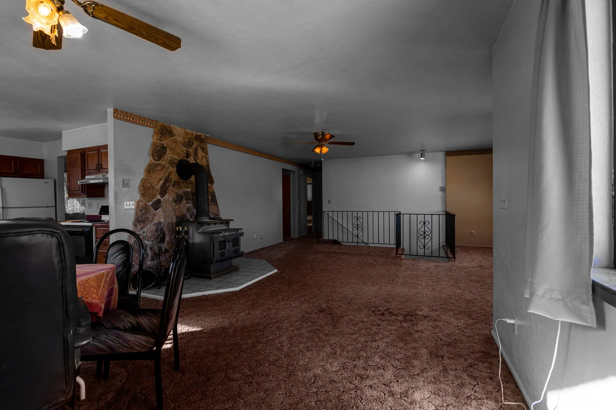 Carpeted living room with a wood stove and a ceiling fan