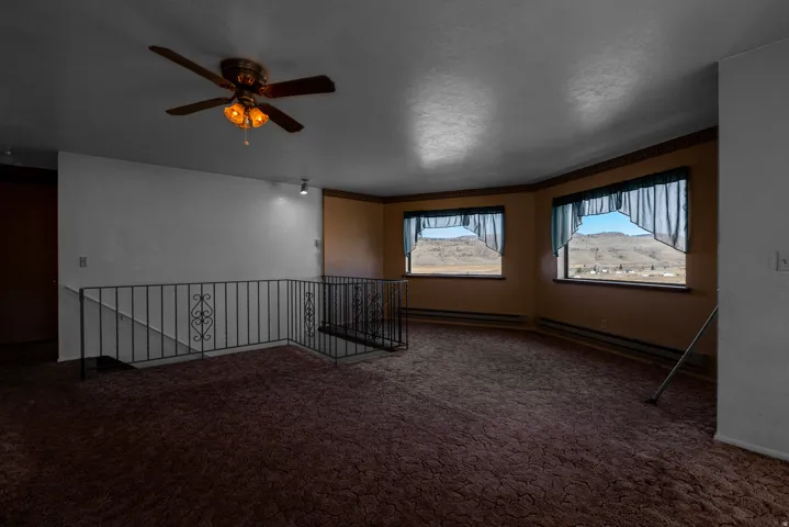 Carpeted empty room with a baseboard radiator and a ceiling fan