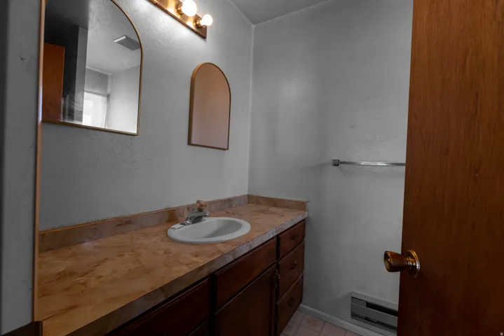 Half bathroom featuring a textured wall, vanity, and a baseboard radiator