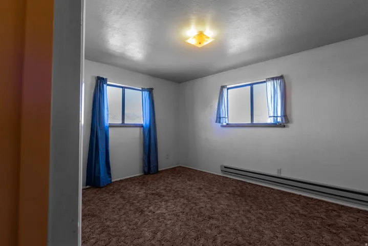 Carpeted empty room with baseboard heating and a textured ceiling