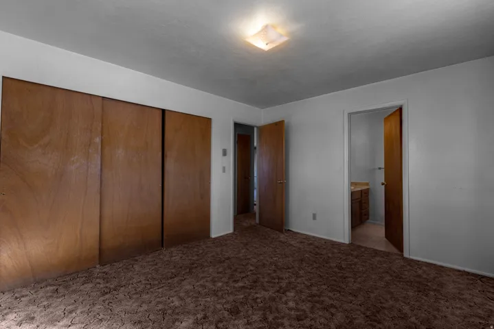 Unfurnished bedroom featuring light colored carpet, a closet, and ensuite bathroom
