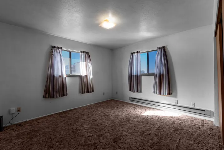 Carpeted spare room featuring a baseboard radiator and a textured ceiling