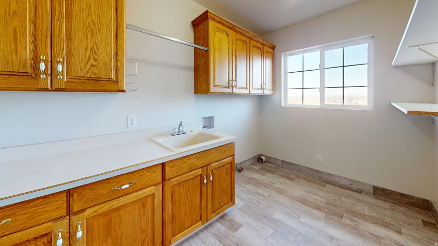 Laundry room with washer hookup, cabinet space, and light wood-style floors