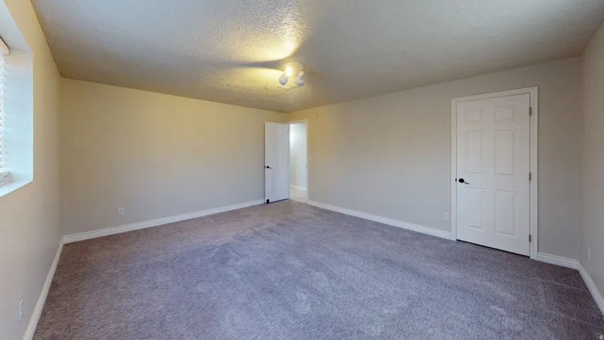 Carpeted spare room with a textured ceiling and baseboards