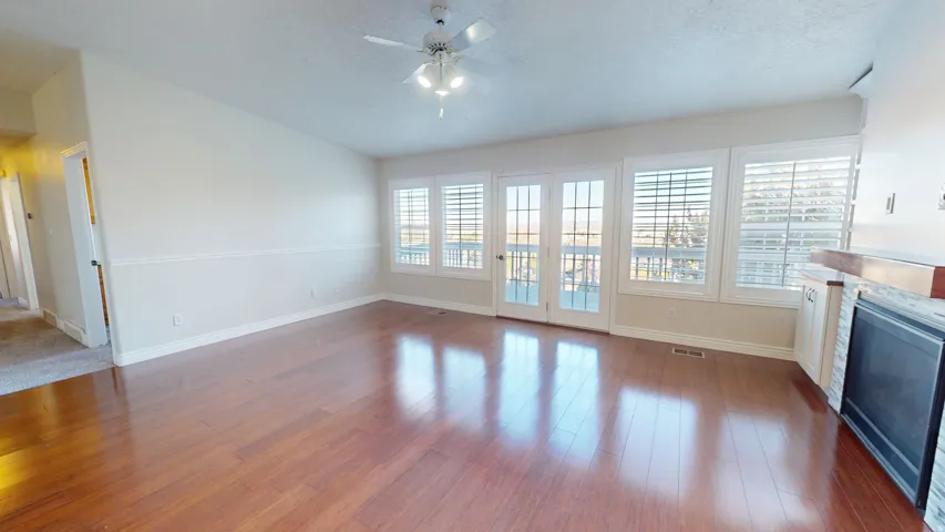 Unfurnished living room featuring a glass covered fireplace, wood finished floors, a textured ceiling, and a ceiling fan