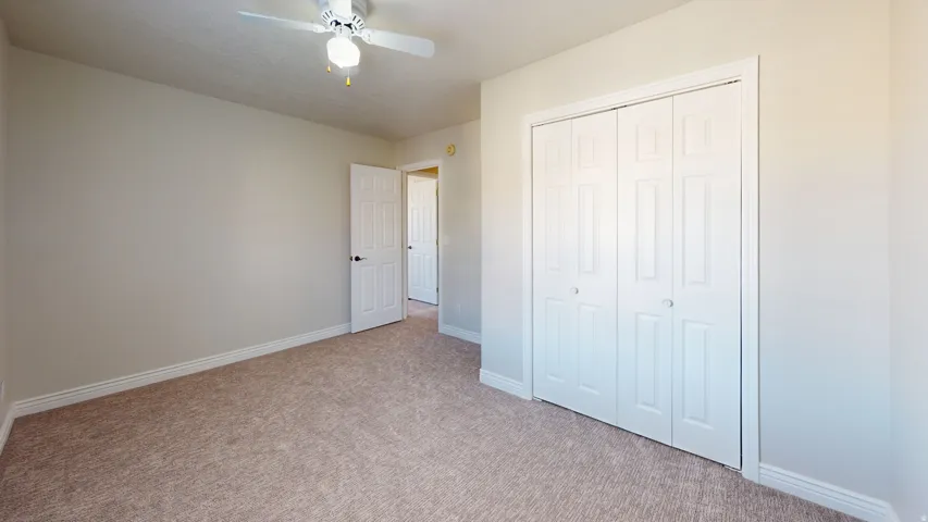 Unfurnished bedroom with carpet flooring, a closet, and ceiling fan