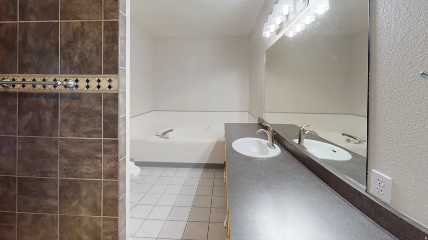 Bathroom featuring vanity, a bath, and light tile patterned flooring