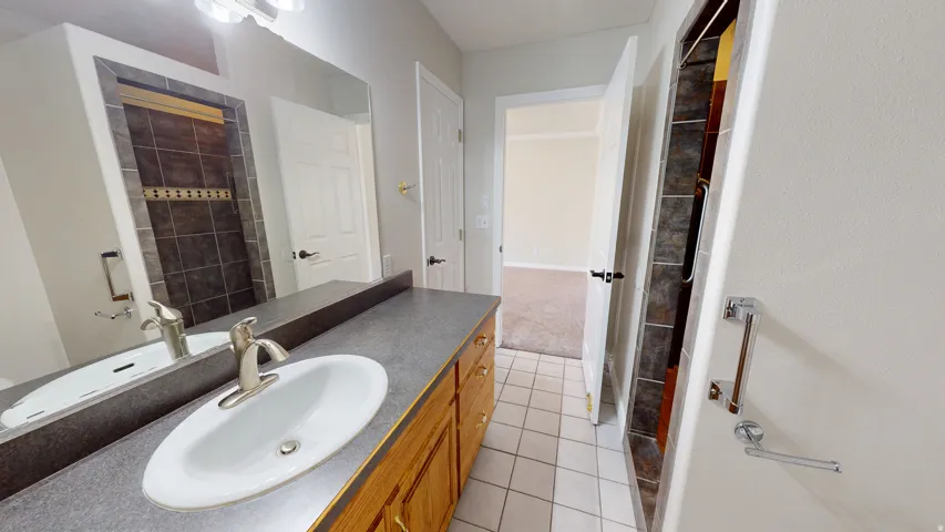 Full bath featuring vanity, light tile patterned flooring, and a shower