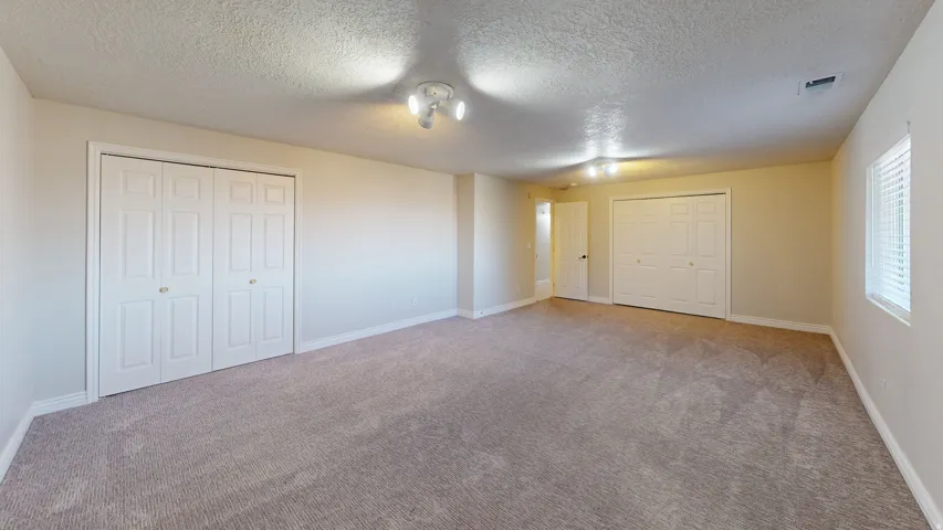 Unfurnished bedroom with multiple closets, a textured ceiling, and carpet