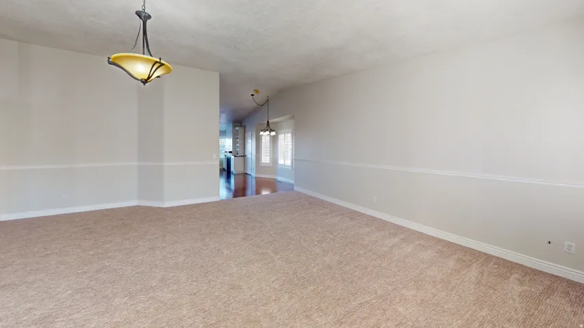 Carpeted spare room featuring a chandelier, lofted ceiling, and a textured ceiling
