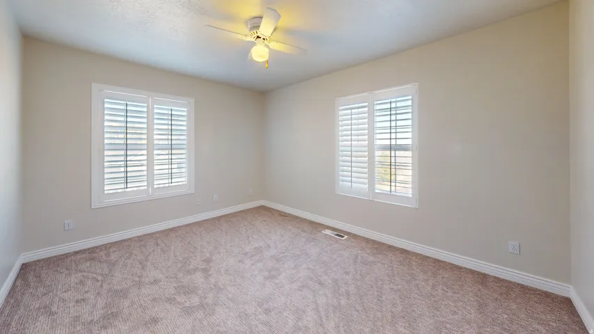 Carpeted spare room with healthy amount of natural light and ceiling fan