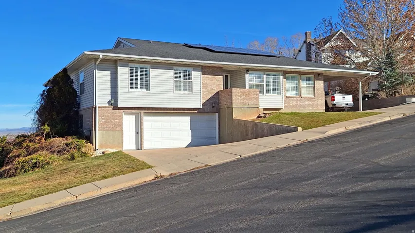 View of front facade with brick siding, solar panels, concrete driveway, a garage, and a front yard