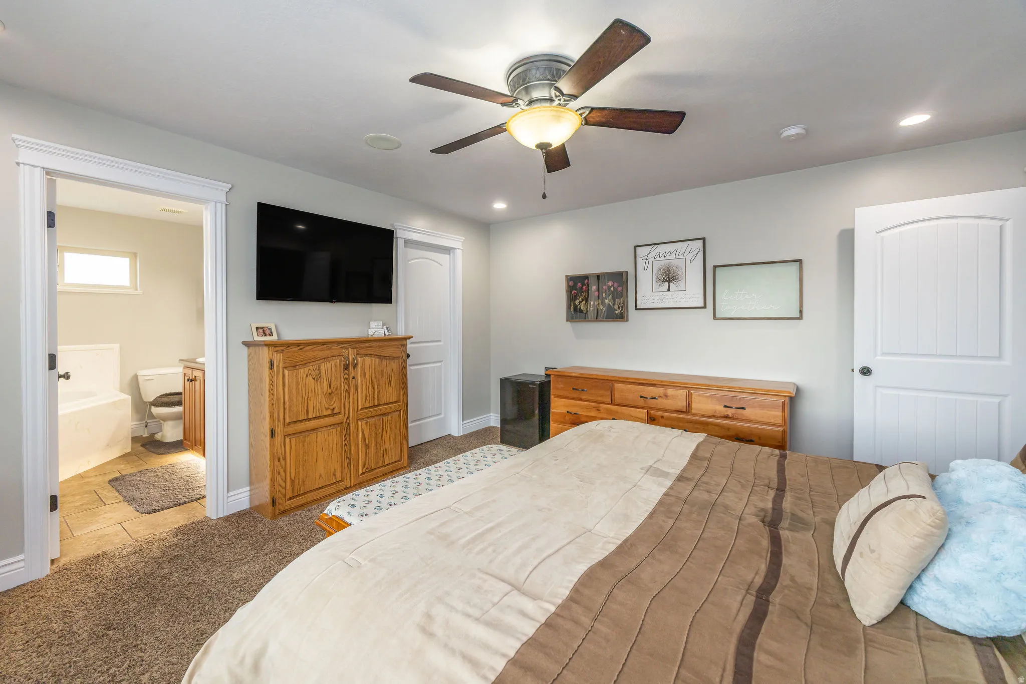 Bedroom featuring a ceiling fan, light colored carpet, and connected bathroom