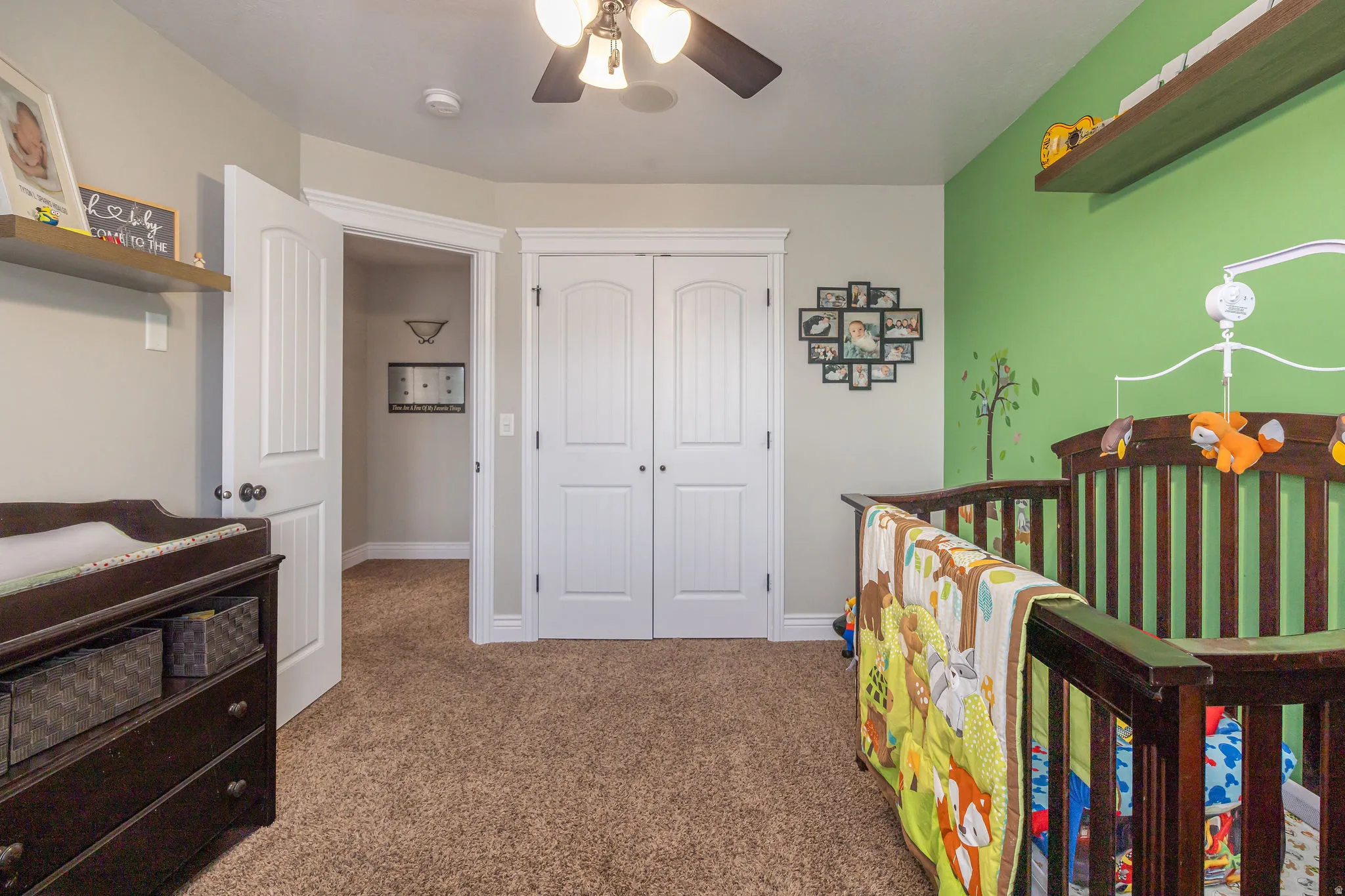 Bedroom with a nursery area, carpet flooring, a closet, and ceiling fan