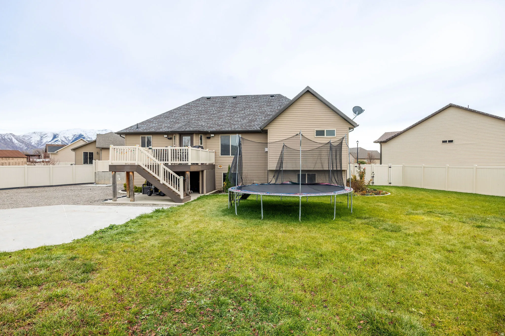 Rear view of house with a fenced backyard, a trampoline, a patio, a deck, and stairs