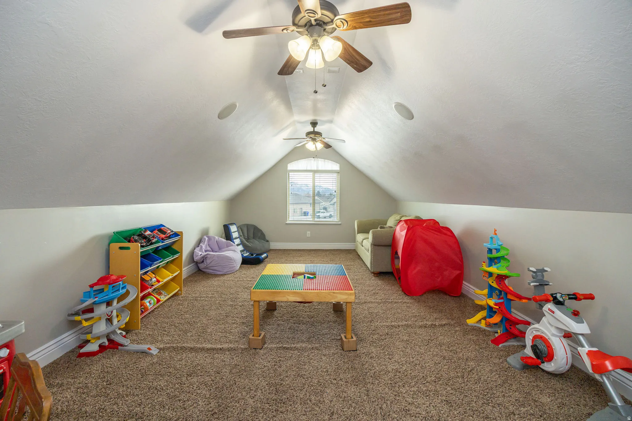 Rec room with carpet, lofted ceiling, a textured ceiling, and a ceiling fan