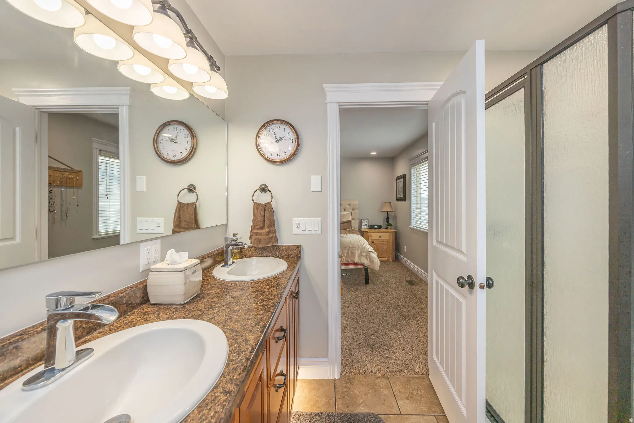 Full bath with double vanity, a shower stall, ensuite bath, light carpet, and light tile patterned flooring