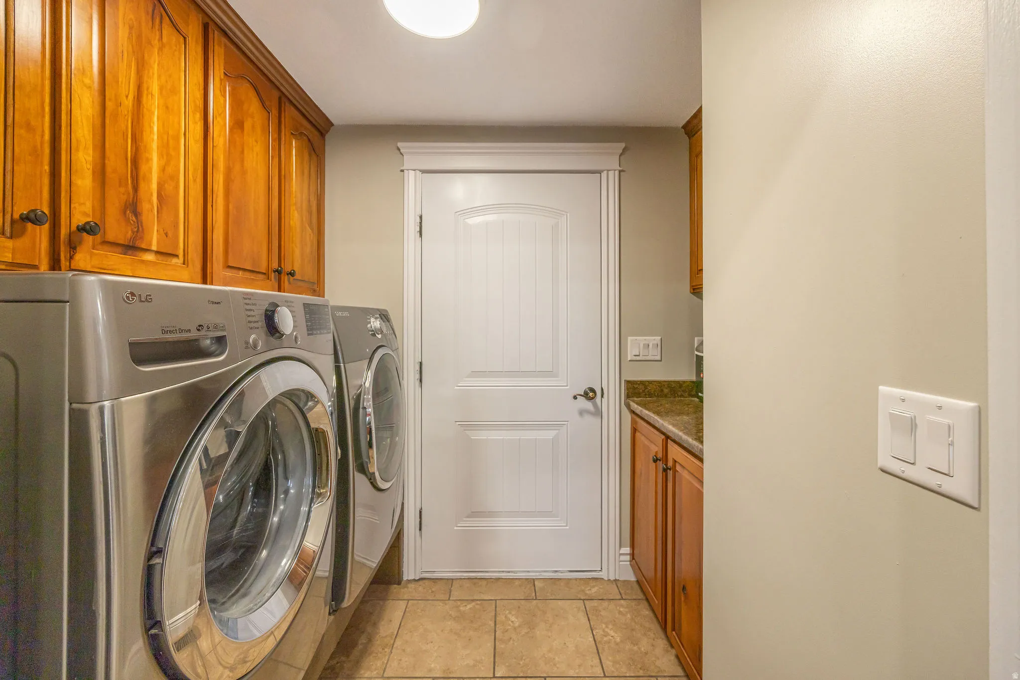 Laundry area featuring light tile patterned flooring, washer and dryer, and cabinet space