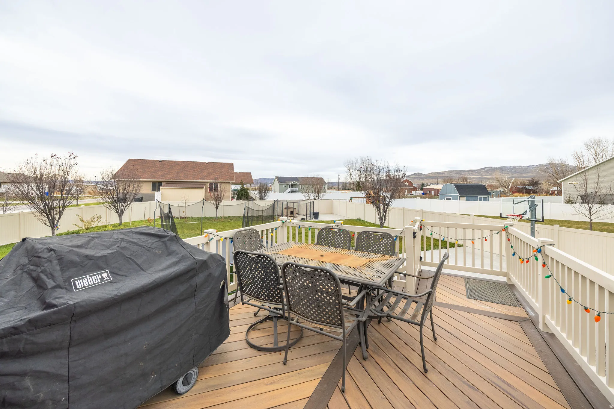 Wooden terrace featuring outdoor dining area, a grill, and a fenced backyard